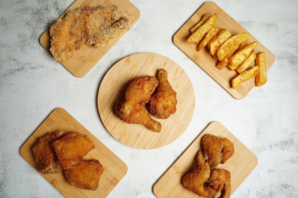 Flat lay of fried chicken chop, chicken drumsticks, and fries on wooden boards. Flat lay of fried chicken chop, chicken drumsticks, and fries on wooden boards.