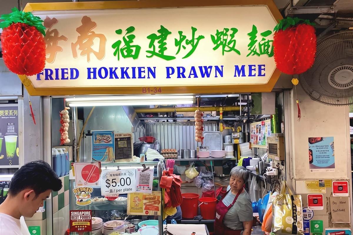 Store front with yellow and green chinese writings on signage beside red hanging decorations Store front with yellow and green chinese writings on signage beside red hanging decorations