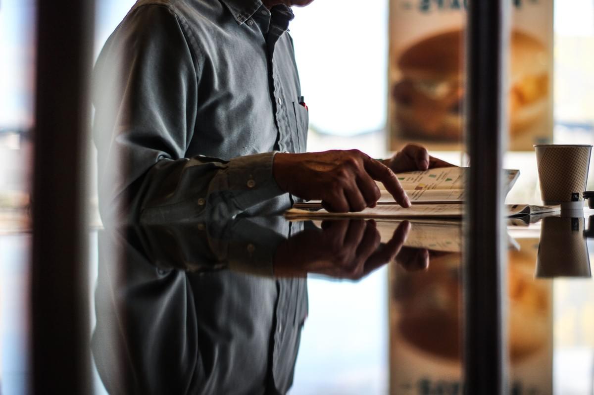 Person reading a menu thoughtfully at a restaurant table. Person reading a menu thoughtfully at a restaurant table.