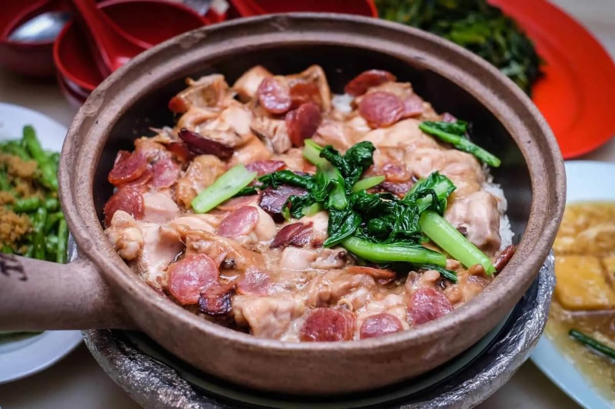 A bowl of Claypot Chicken Rice topped with tender meat and colorful vegetables, showcasing a traditional Singaporean dish. A bowl of Claypot Chicken Rice topped with tender meat and colorful vegetables, showcasing a traditional Singaporean dish.