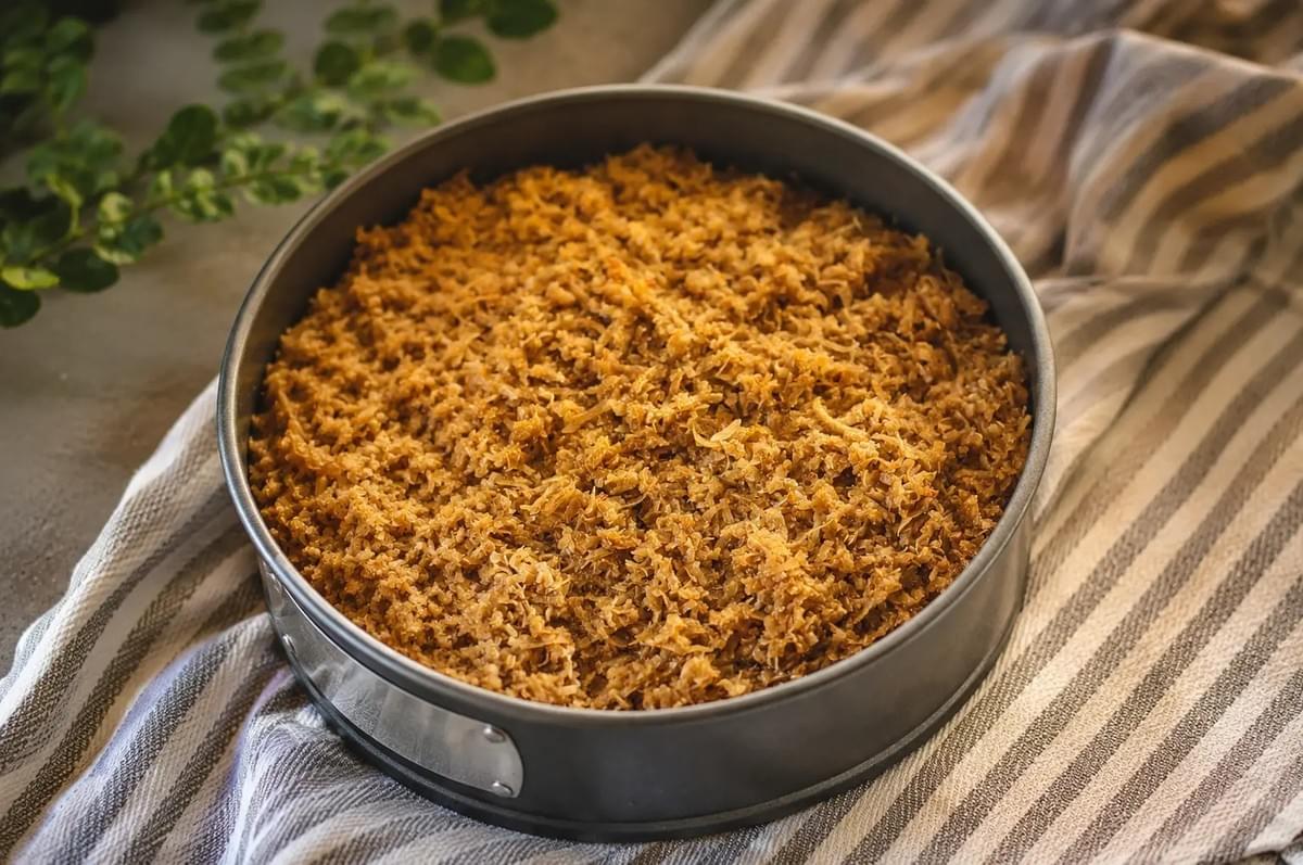 A freshly baked round coconut cake cooled directly inside a springform baking pan. A freshly baked round coconut cake cooled directly inside a springform baking pan.