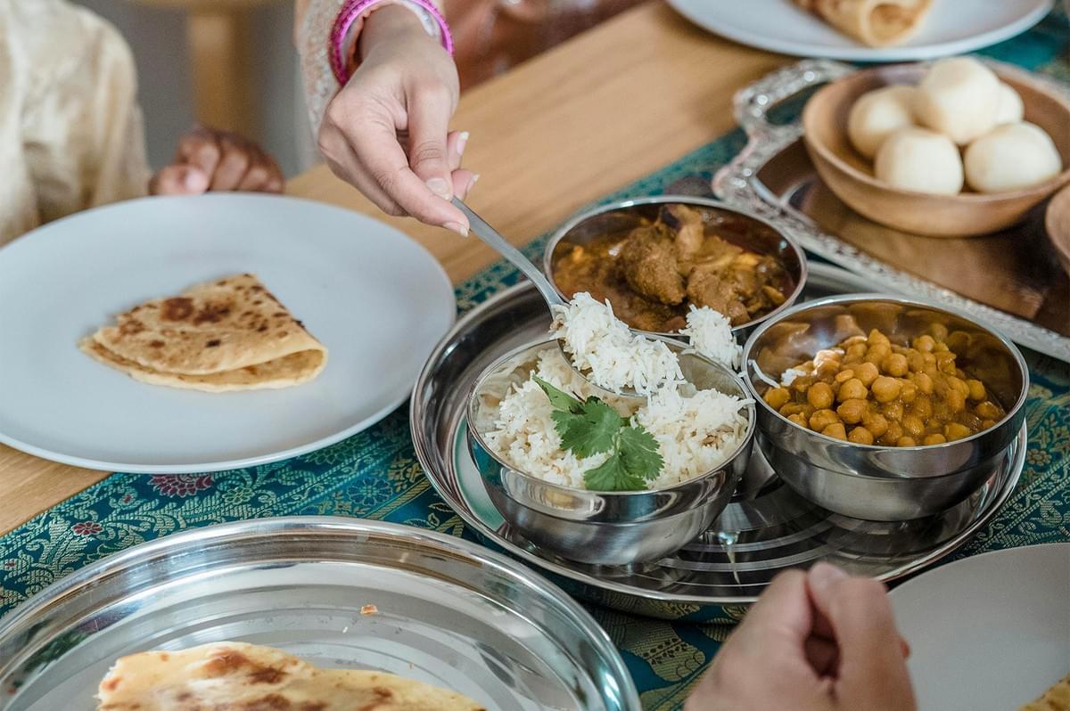 Traditional meal served with basmati rice, chickpea curry (chana masala), meat curry, and flatbread on a dining table. Traditional meal served with basmati rice, chickpea curry (chana masala), meat curry, and flatbread on a dining table.