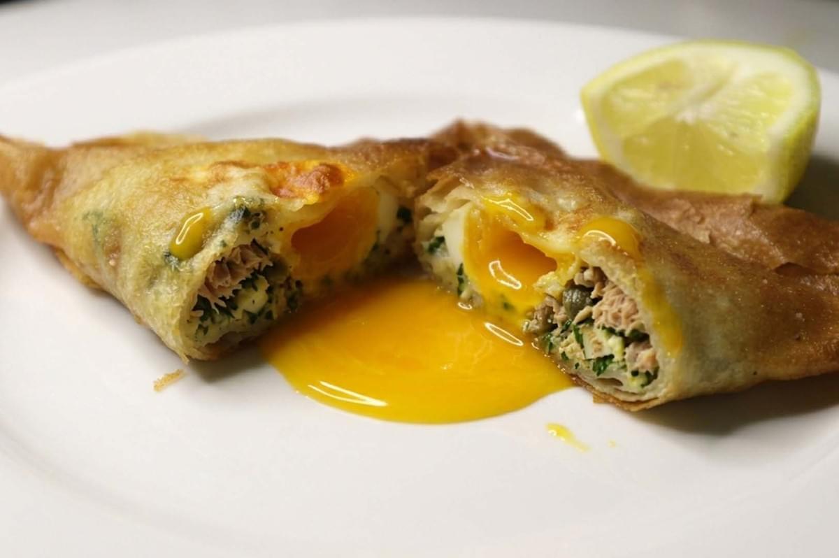 Crispy brik pastry cut open with runny egg yolk and tuna filling Crispy brik pastry cut open with runny egg yolk and tuna filling