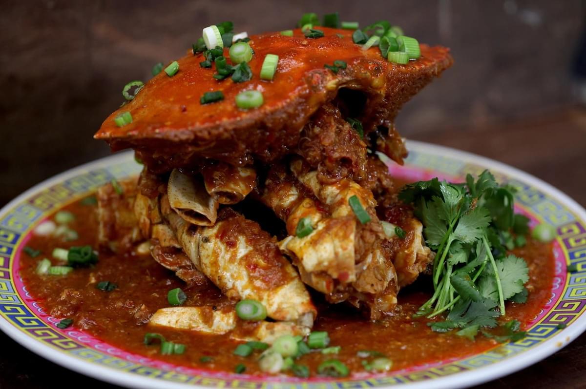 A serving of Chili Crab on a plate, topped with fresh green onions, highlighting the dish's rich flavors and textures. A serving of Chili Crab on a plate, topped with fresh green onions, highlighting the dish's rich flavors and textures.