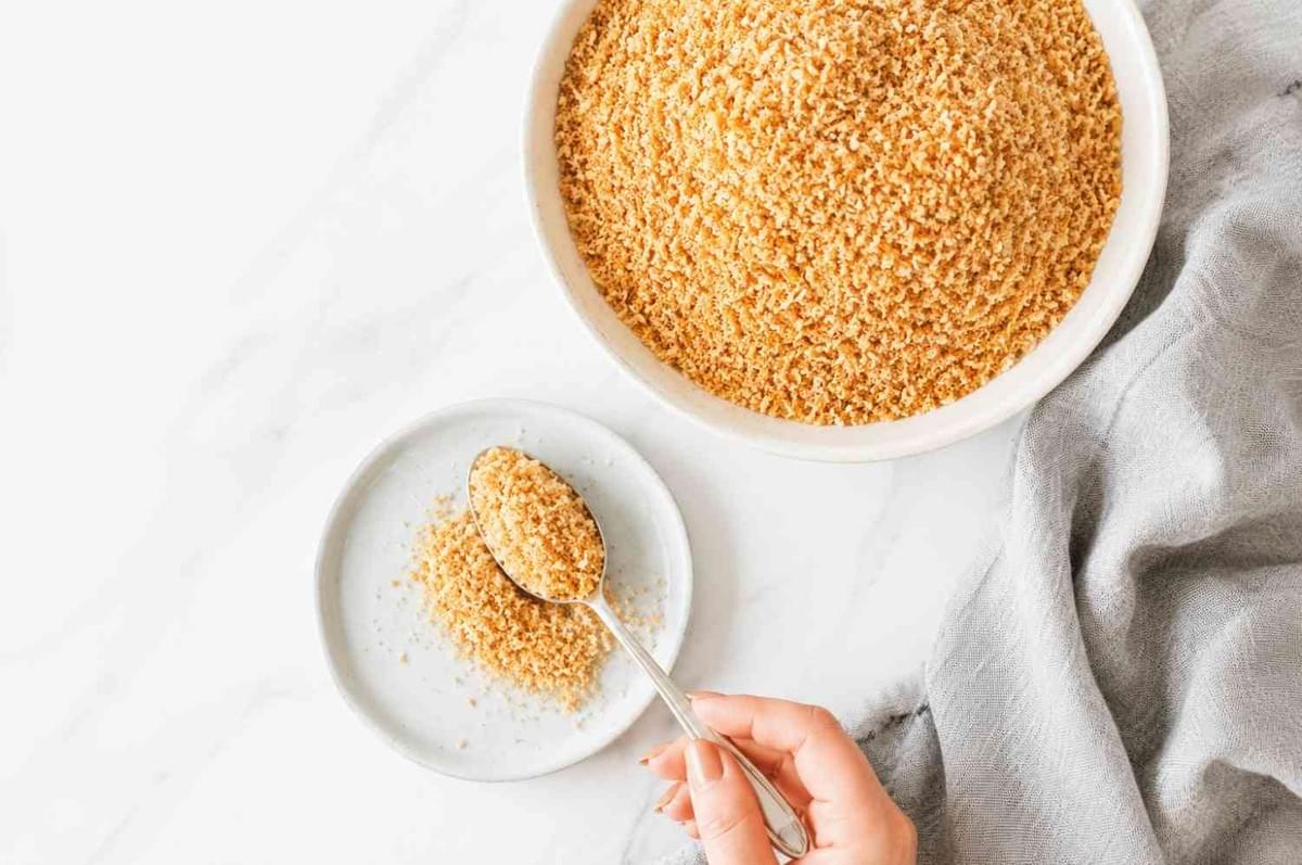 Top-down view of panko breadcrumbs in a bowl with a small scoop on a white marble counter. Top-down view of panko breadcrumbs in a bowl with a small scoop on a white marble counter.
