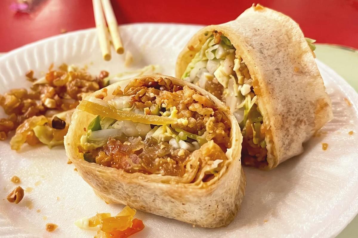 Close up photo of sliced popiah filled with beans and vegetables on a white styrofoam plate Close up photo of sliced popiah filled with beans and vegetables on a white styrofoam plate
