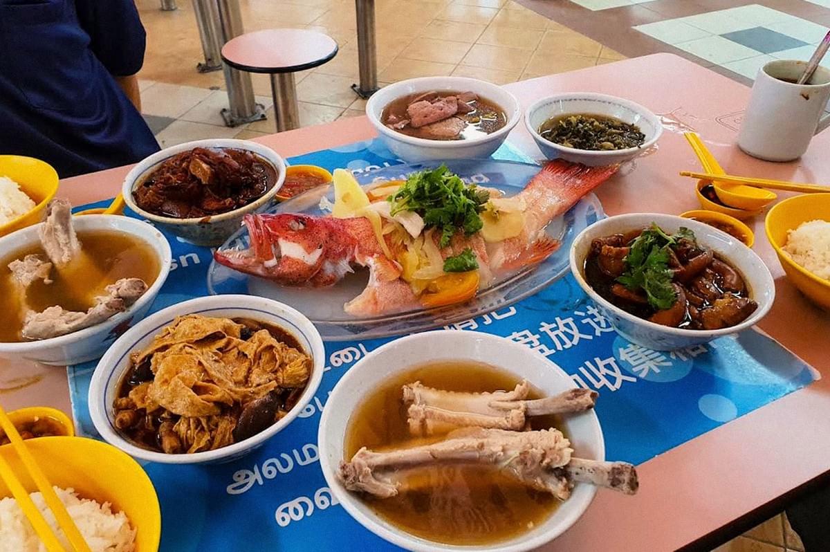 A traditional meal spread featuring steamed fish, pork soup, braised meat, vegetables, and rice. A traditional meal spread featuring steamed fish, pork soup, braised meat, vegetables, and rice.