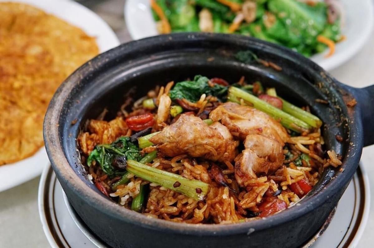 A serving of Claypot Chicken Rice, showcasing rice mixed with vibrant vegetables in a traditional bowl. A serving of Claypot Chicken Rice, showcasing rice mixed with vibrant vegetables in a traditional bowl.