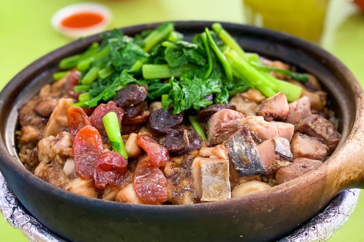 A serving of Claypot Chicken Rice, showcasing succulent meat and fresh vegetables in a traditional bowl. A serving of Claypot Chicken Rice, showcasing succulent meat and fresh vegetables in a traditional bowl.