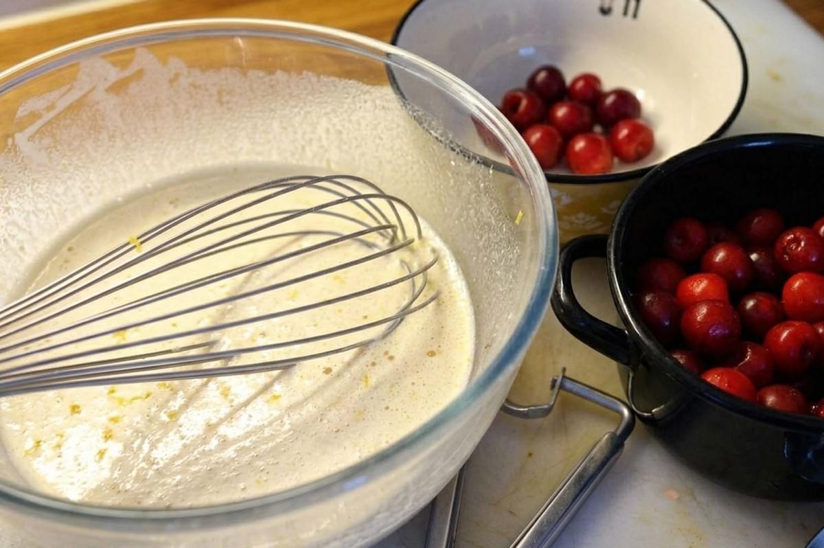 Whisked batter bowl next to fresh cherries Whisked batter bowl next to fresh cherries