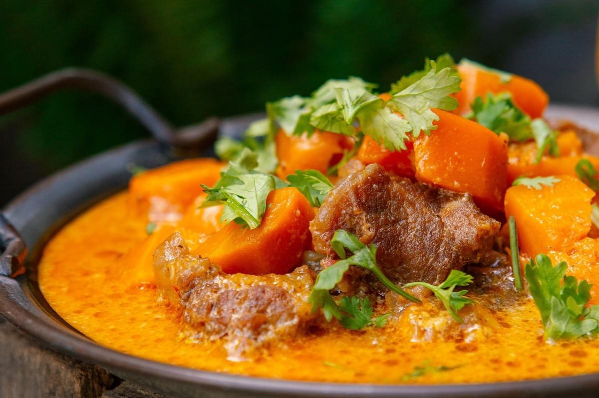 Close-up of a comforting bowl of slow-simmered halal beef stew with carrots and fresh herbs in a rustic pot. Close-up of a comforting bowl of slow-simmered halal beef stew with carrots and fresh herbs in a rustic pot.
