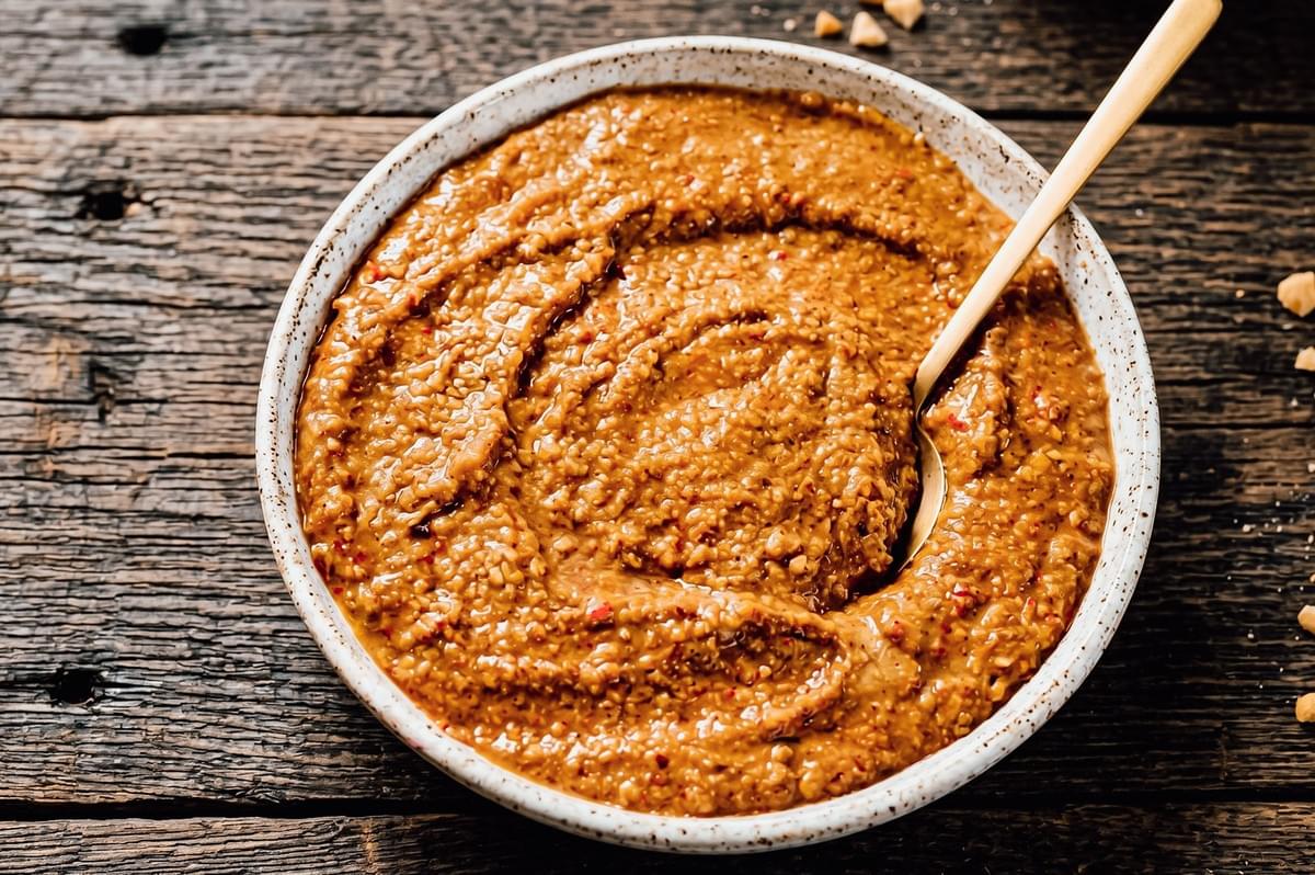 Overhead close-up shot of rich Indonesian peanut sauce in a bowl with visible crushed peanuts, served as a dipping sauce for chicken satay Overhead close-up shot of rich Indonesian peanut sauce in a bowl with visible crushed peanuts, served as a dipping sauce for chicken satay