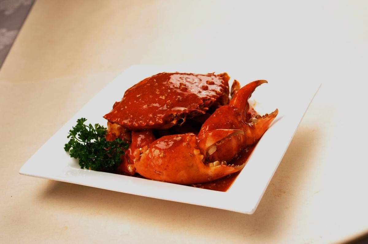 A whole chili crab displayed on a white plate, highlighting its rich color and appetizing presentation. A whole chili crab displayed on a white plate, highlighting its rich color and appetizing presentation.