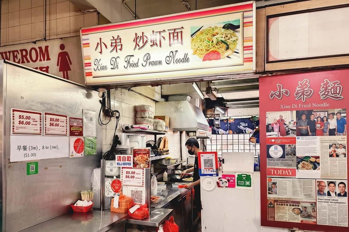 Striped storefront banner of Xiao Di Fried Prawn Noodle with noodle photo beside and posters about store history and food prices Striped storefront banner of Xiao Di Fried Prawn Noodle with noodle photo beside and posters about store history and food prices