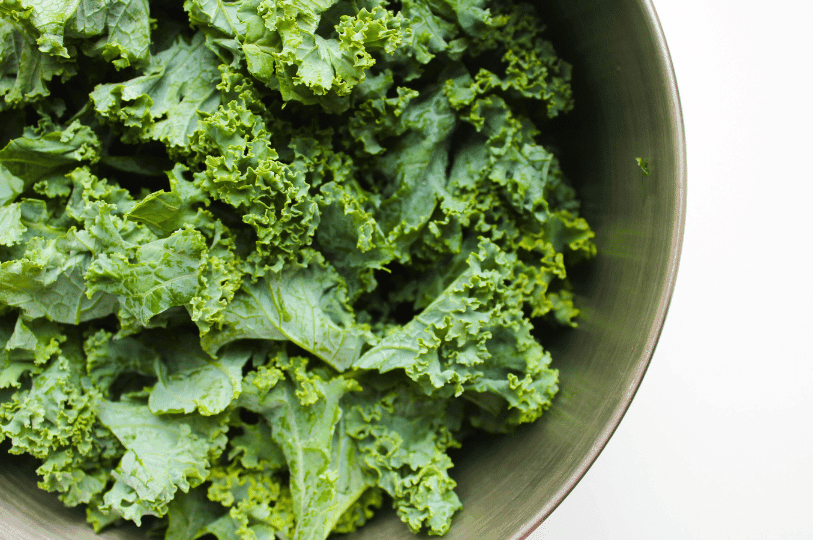 A close-up shot of fresh, leafy green kale packed into a dark metal bowl, highlighting the intricate ruffles of the leaves. A close-up shot of fresh, leafy green kale packed into a dark metal bowl, highlighting the intricate ruffles of the leaves.