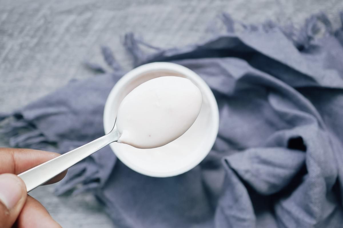 Top-down macro close-up shot of spoon scooping plain yogurt, representing ingredient substitution, food exploration, and adaptability in international grocery shopping with children Top-down macro close-up shot of spoon scooping plain yogurt, representing ingredient substitution, food exploration, and adaptability in international grocery shopping with children
