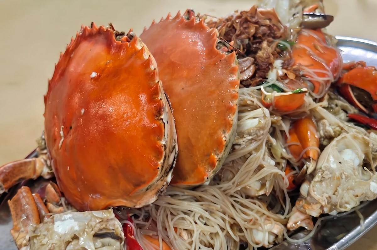 A platter of Singapore-style crab bee hoon, featuring large cooked crabs served over a bed of vermicelli noodles. A platter of Singapore-style crab bee hoon, featuring large cooked crabs served over a bed of vermicelli noodles.