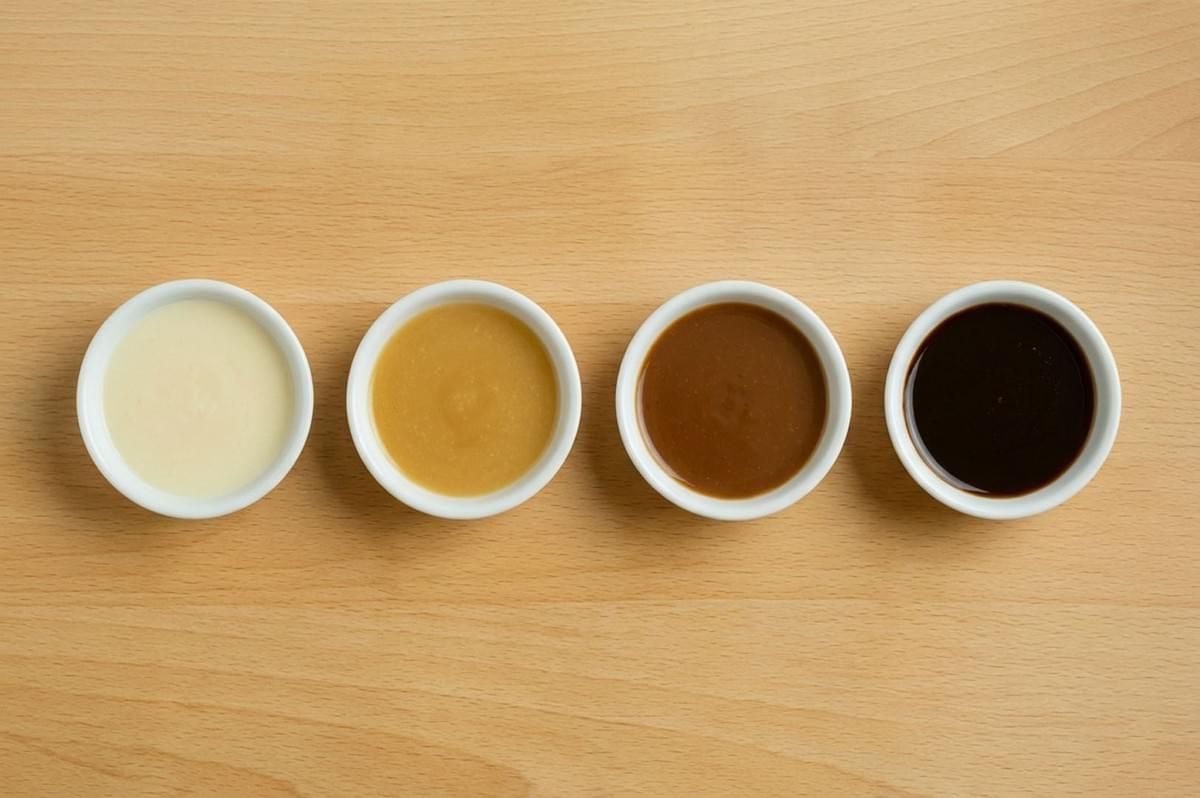 Four ramekins displaying roux color stages from white to dark brown Four ramekins displaying roux color stages from white to dark brown
