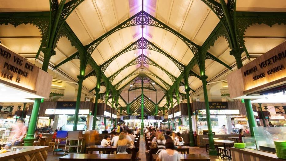This image captures the bustling interior of Lau Pa Sat, a historic food center in Singapore, featuring ornate green Victorian ironwork arches over a crowded dining area with various local food stalls. This image captures the bustling interior of Lau Pa Sat, a historic food center in Singapore, featuring ornate green Victorian ironwork arches over a crowded dining area with various local food stalls.