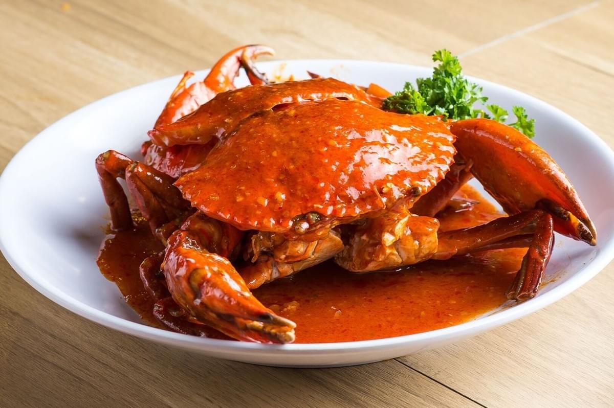 A vibrant crab resting on a plate, generously topped with spicy chili sauce, representing a classic Chili Crab meal. A vibrant crab resting on a plate, generously topped with spicy chili sauce, representing a classic Chili Crab meal.