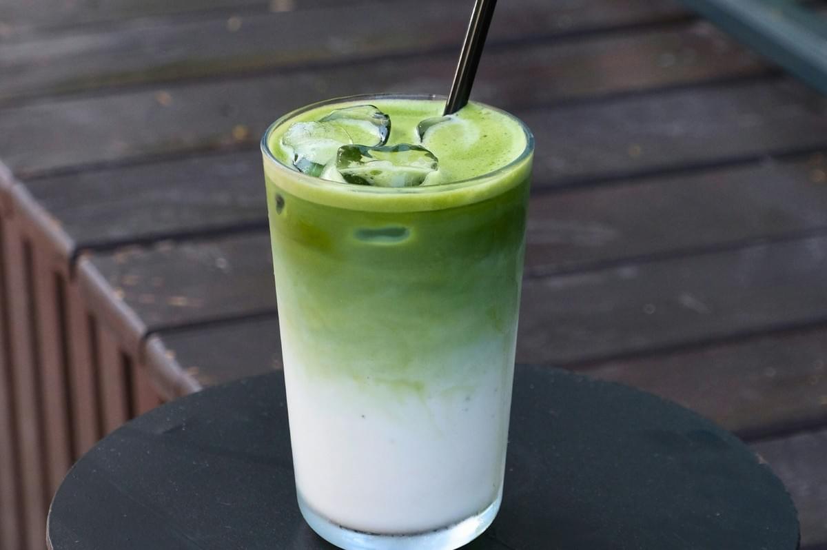 Iced green tea latte in a glass on a table at a cafe. Iced green tea latte in a glass on a table at a cafe.
