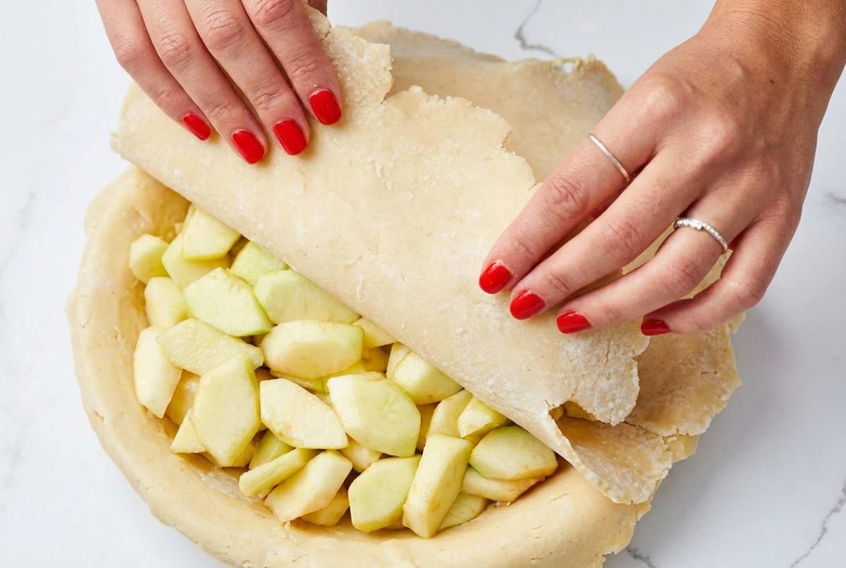 Whole Dutch apple pie with a woven lattice crust on a dark tray, missing a slice. Whole Dutch apple pie with a woven lattice crust on a dark tray, missing a slice.
