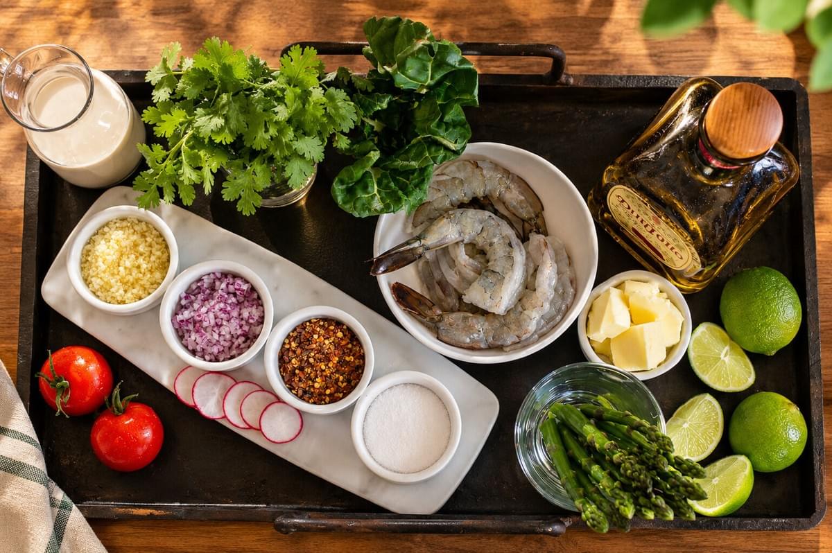 Flat lay of raw shrimp, limes, herbs, butter, and seasonings organized on a wooden tray. Flat lay of raw shrimp, limes, herbs, butter, and seasonings organized on a wooden tray.