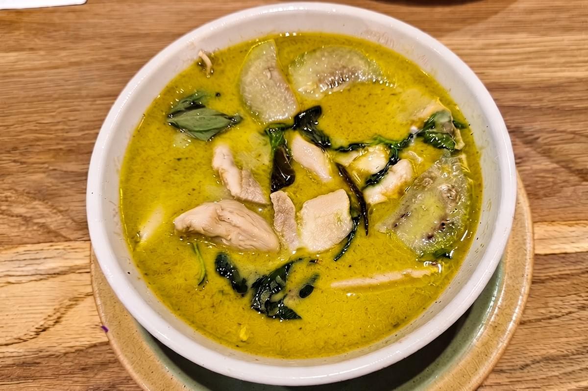 Bowl of creamy halal Thai green curry chicken with eggplant and basil at Siam Kitchen Khatib. Bowl of creamy halal Thai green curry chicken with eggplant and basil at Siam Kitchen Khatib.