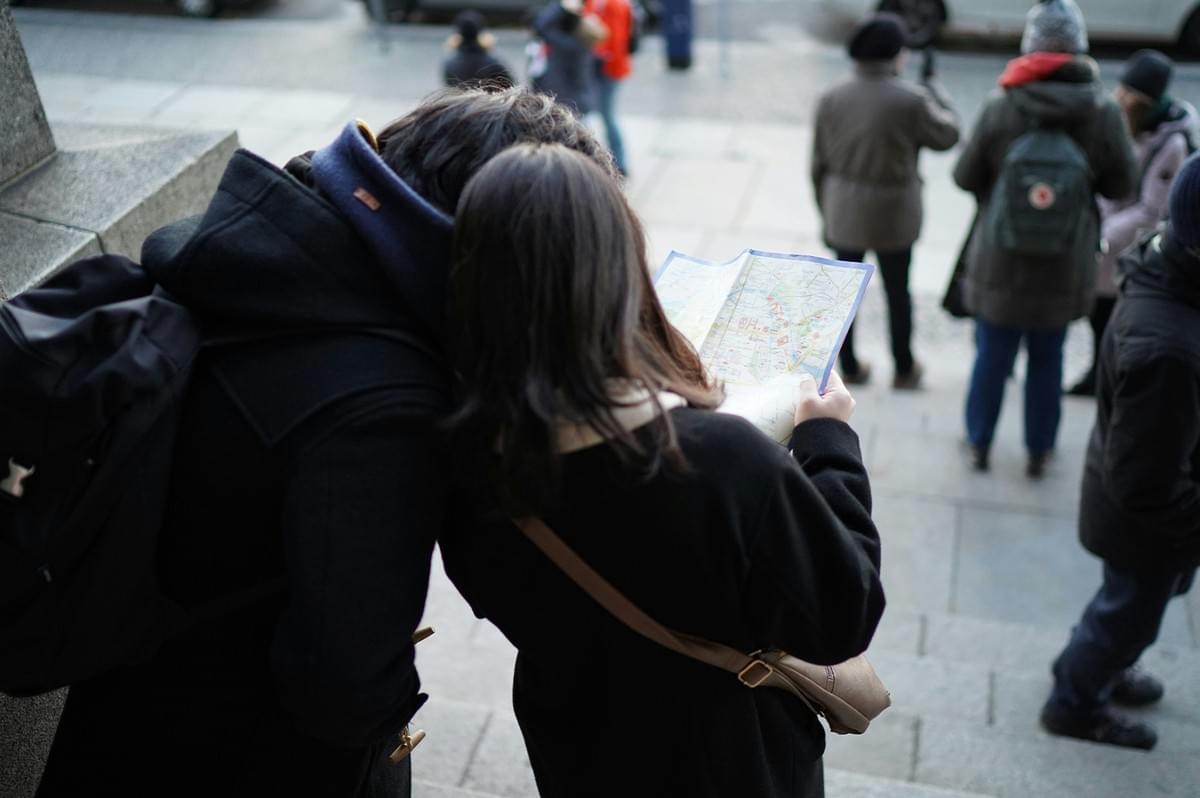Two travelers looking at a map while exploring a city street. Two travelers looking at a map while exploring a city street.