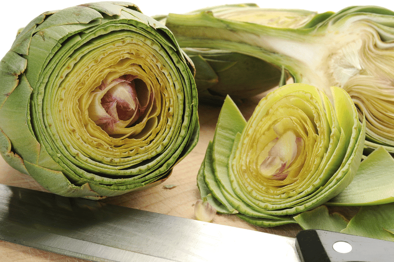 A cross-section of a raw artichoke sliced in half horizontally on a wooden cutting board next to a chef's knife, revealing the intricate inner layers and the pale purple heart. A cross-section of a raw artichoke sliced in half horizontally on a wooden cutting board next to a chef's knife, revealing the intricate inner layers and the pale purple heart.