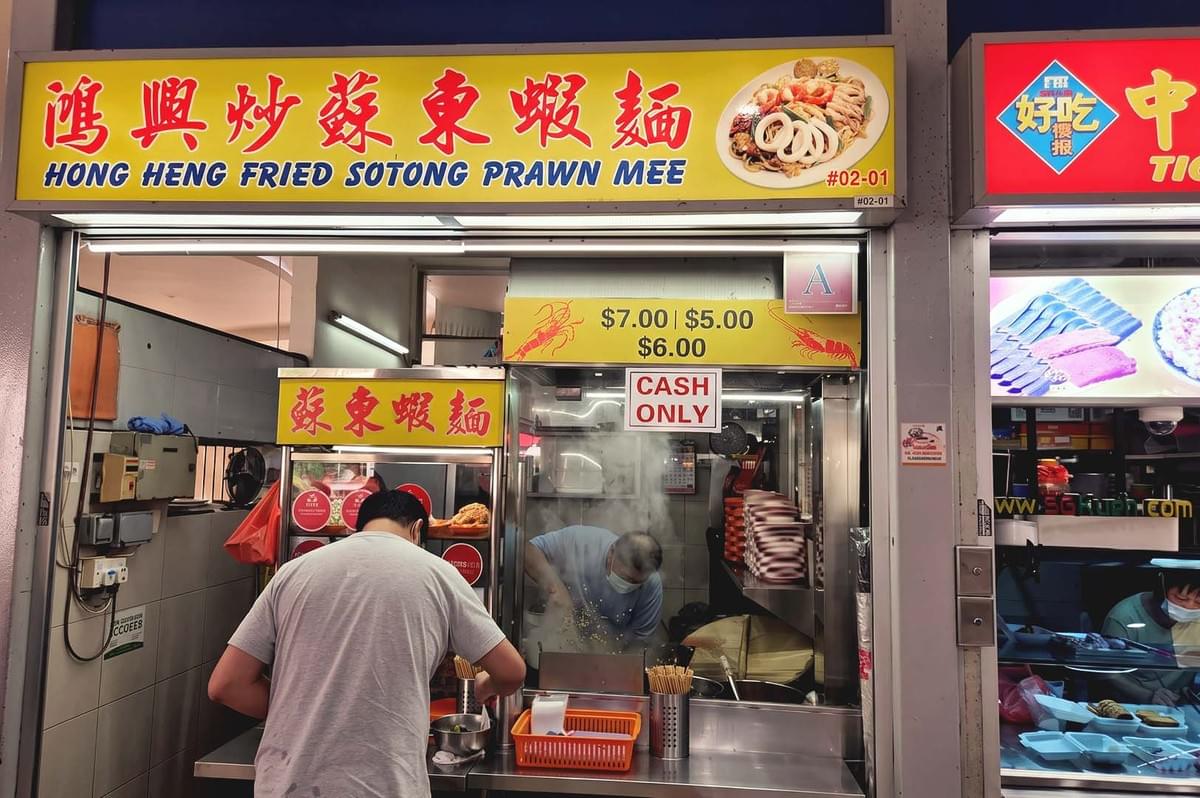 Yellow LED lighted signage of Hong Heng Friend Sotong Prawn Mee storefront with red chinese letters Yellow LED lighted signage of Hong Heng Friend Sotong Prawn Mee storefront with red chinese letters