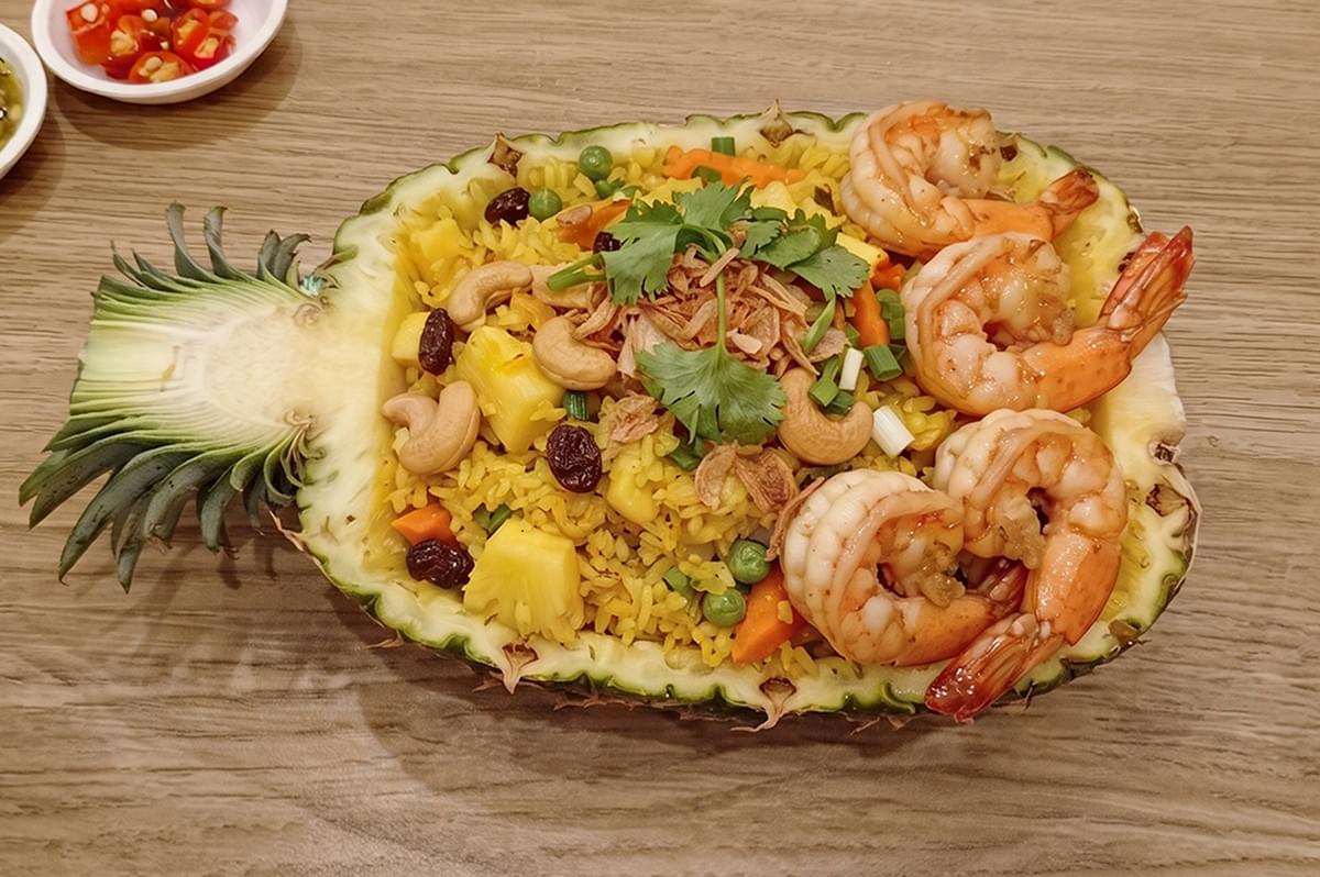 Delicious Thai Pineapple Fried Rice with Prawns served inside a carved pineapple bowl. Delicious Thai Pineapple Fried Rice with Prawns served inside a carved pineapple bowl.
