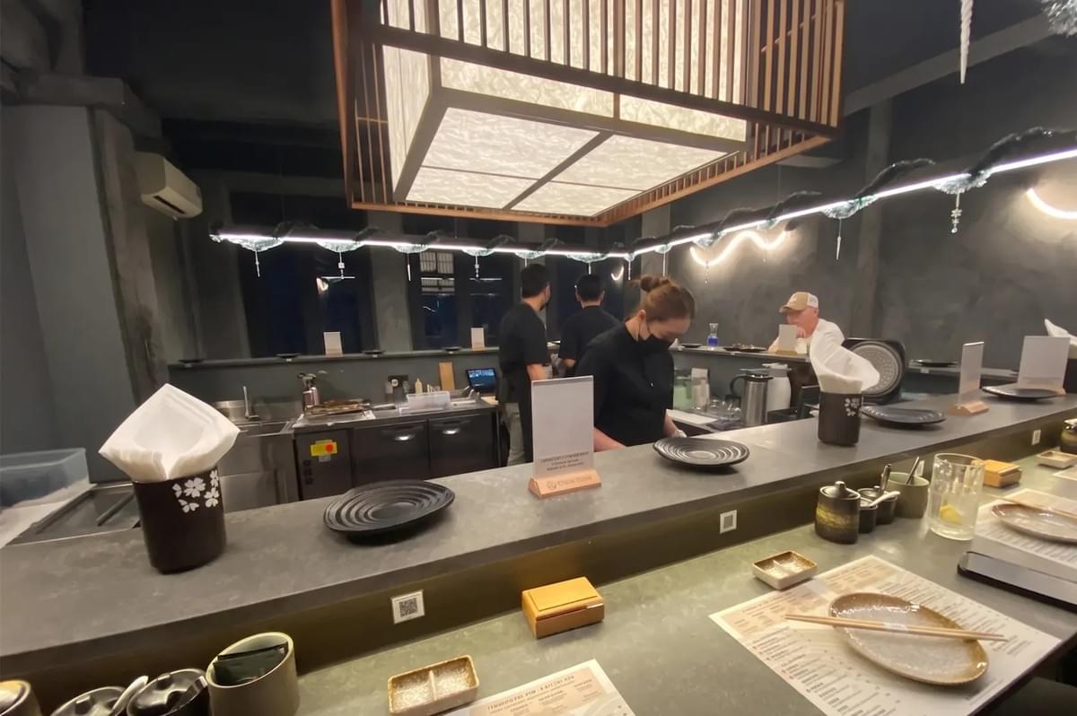 Toku Nori restaurant interior featuring a modern handroll bar counter with place settings and staff. Toku Nori restaurant interior featuring a modern handroll bar counter with place settings and staff.