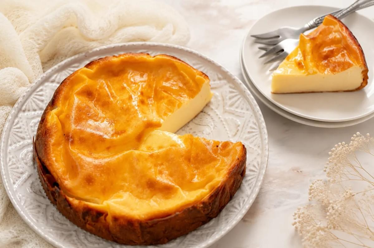 Golden burnt Basque cheesecake on a decorative plate with a slice served nearby. Golden burnt Basque cheesecake on a decorative plate with a slice served nearby.