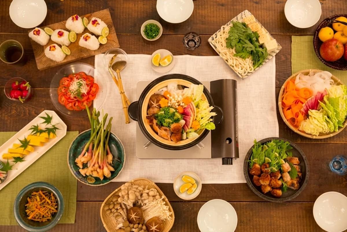 Overhead view of a hot pot hotpot setup surrounded by fresh vegetables, rice balls, and side dishes. Overhead view of a hot pot hotpot setup surrounded by fresh vegetables, rice balls, and side dishes.