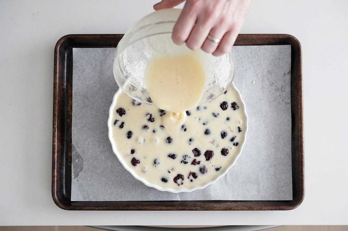 Pouring batter over berries in baking dish Pouring batter over berries in baking dish