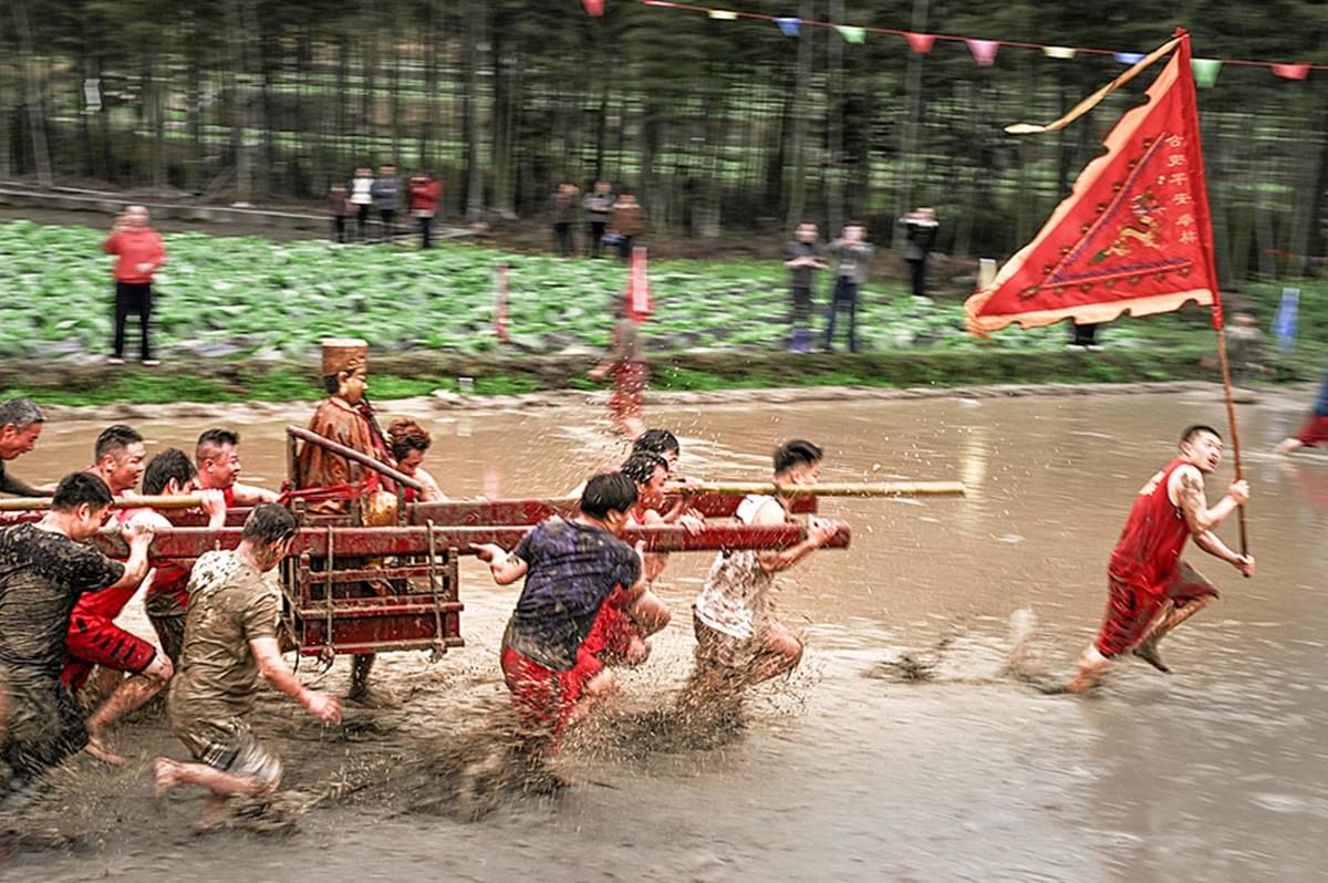 Men running in pool of mud with a flag Men running in pool of mud with a flag