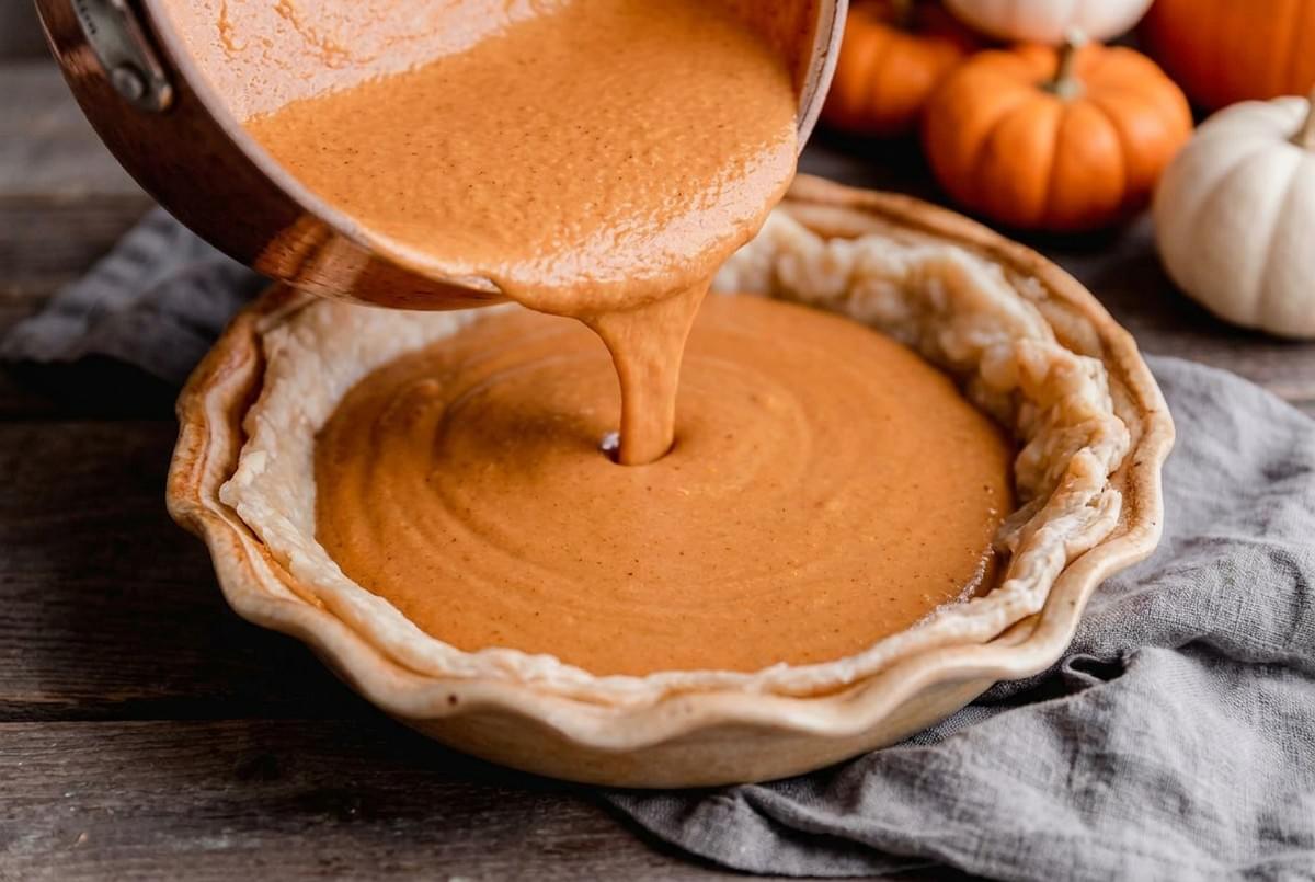 Whole freshly baked pumpkin pie surrounded by mini pumpkins and autumn leaves. Whole freshly baked pumpkin pie surrounded by mini pumpkins and autumn leaves.
