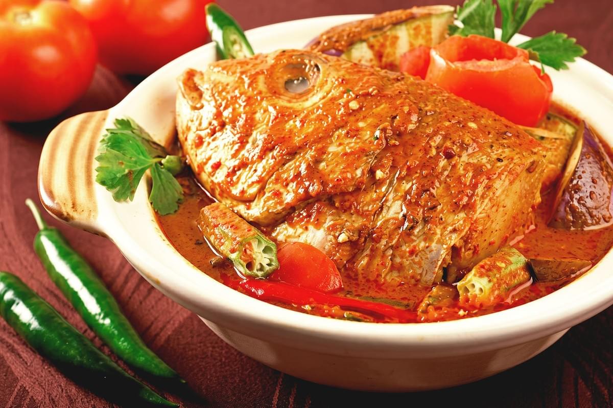 Fish head cooked in red curry sauce garnished with okra, tomatoes and basil Fish head cooked in red curry sauce garnished with okra, tomatoes and basil