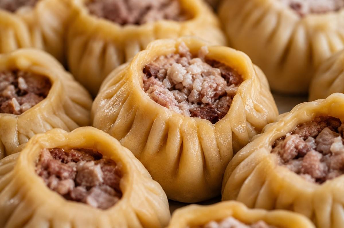 Close-up view of Mongolian buuz dumplings showing the pleated dough and minced meat filling inside Close-up view of Mongolian buuz dumplings showing the pleated dough and minced meat filling inside