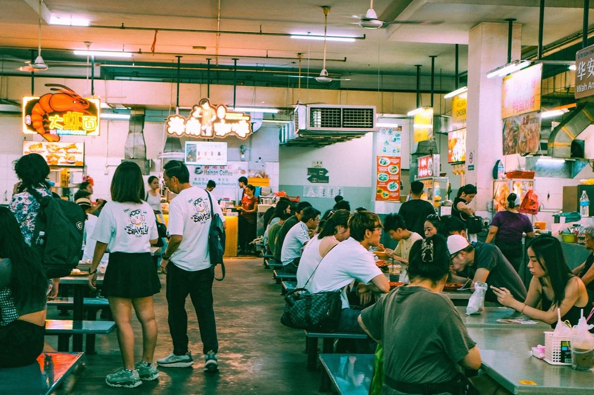 A bustling and vibrant halal food court filled with diverse people sitting at shared tables, enjoying meals together in a relaxed atmosphere. A bustling and vibrant halal food court filled with diverse people sitting at shared tables, enjoying meals together in a relaxed atmosphere.
