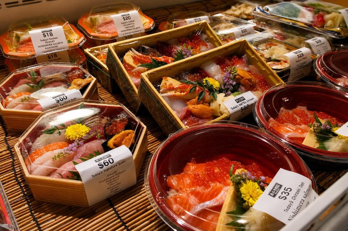 Premium bento boxes filled with sushi, sashimi, and sea urchin displayed on bamboo matting. Premium bento boxes filled with sushi, sashimi, and sea urchin displayed on bamboo matting.