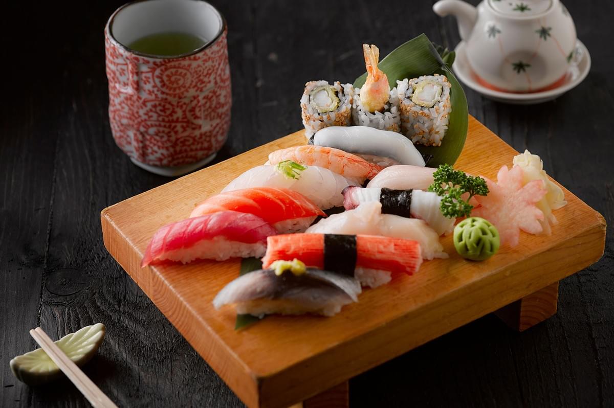 Assorted halal sushi platter served on a wooden board with tea, ideal for dining at Singapore halal sushi spots. Assorted halal sushi platter served on a wooden board with tea, ideal for dining at Singapore halal sushi spots.