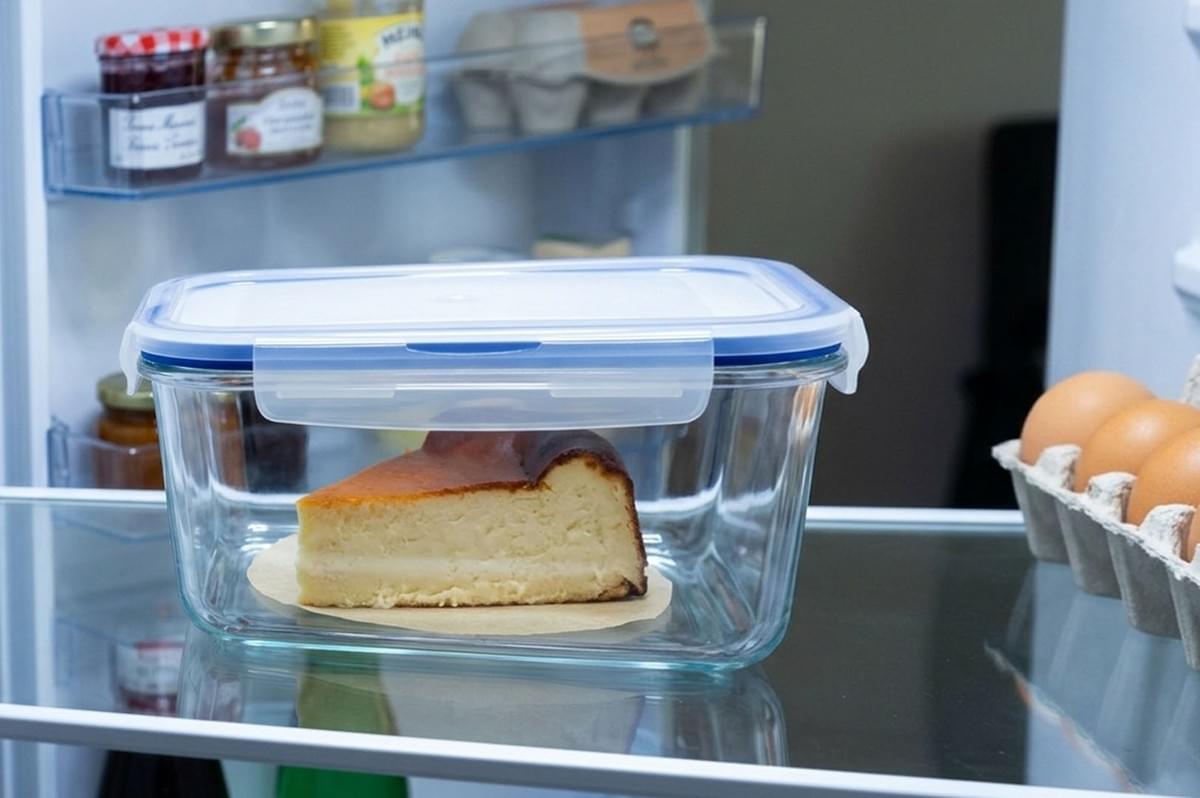 A slice of Basque burnt cheesecake stored in a clear glass container inside a refrigerator A slice of Basque burnt cheesecake stored in a clear glass container inside a refrigerator