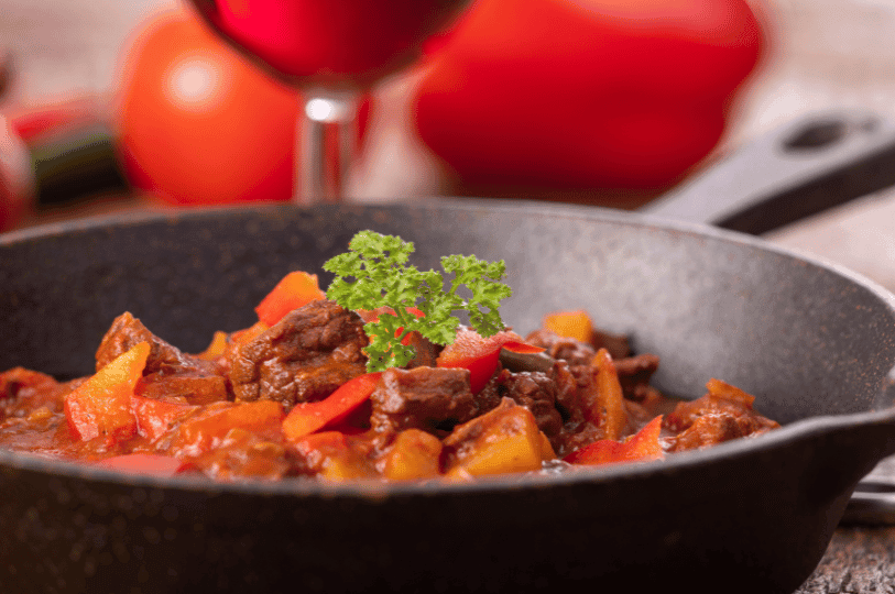 A beautifully styled ceramic bowl filled with savory Jollof rice, tender chunks of beef stew, and a side of sweet, ripe plantains resting on a textured wooden table. A beautifully styled ceramic bowl filled with savory Jollof rice, tender chunks of beef stew, and a side of sweet, ripe plantains resting on a textured wooden table.