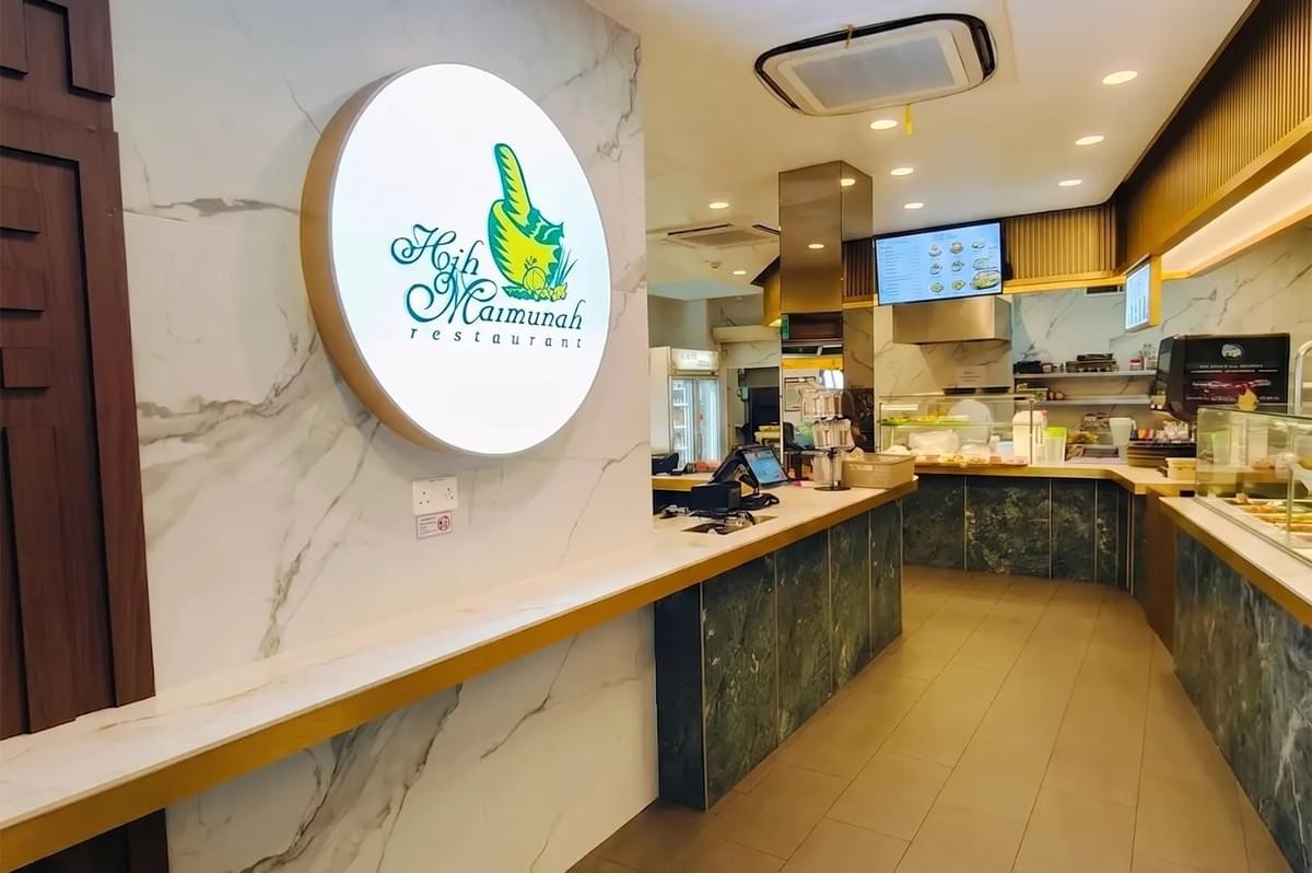 Interior of Hajah Maimunah Restaurant featuring a modern counter and backlit logo sign. Interior of Hajah Maimunah Restaurant featuring a modern counter and backlit logo sign.