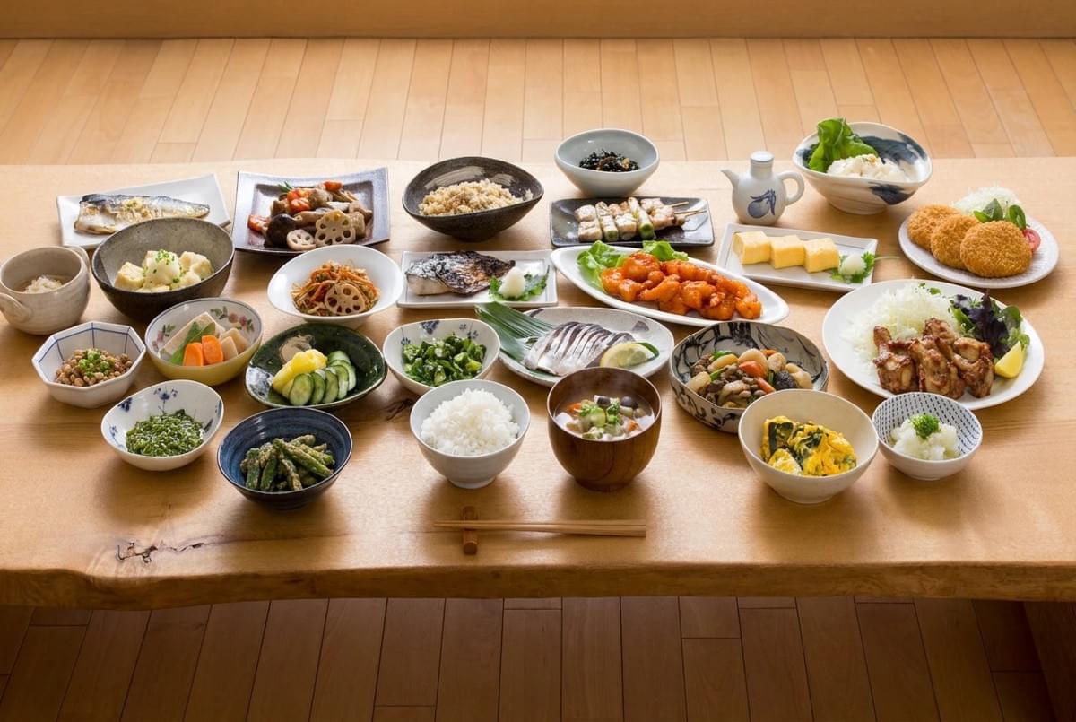 Abundant spread of traditional Japanese dishes, rice, soup, and sides covering a low wooden table. Abundant spread of traditional Japanese dishes, rice, soup, and sides covering a low wooden table.