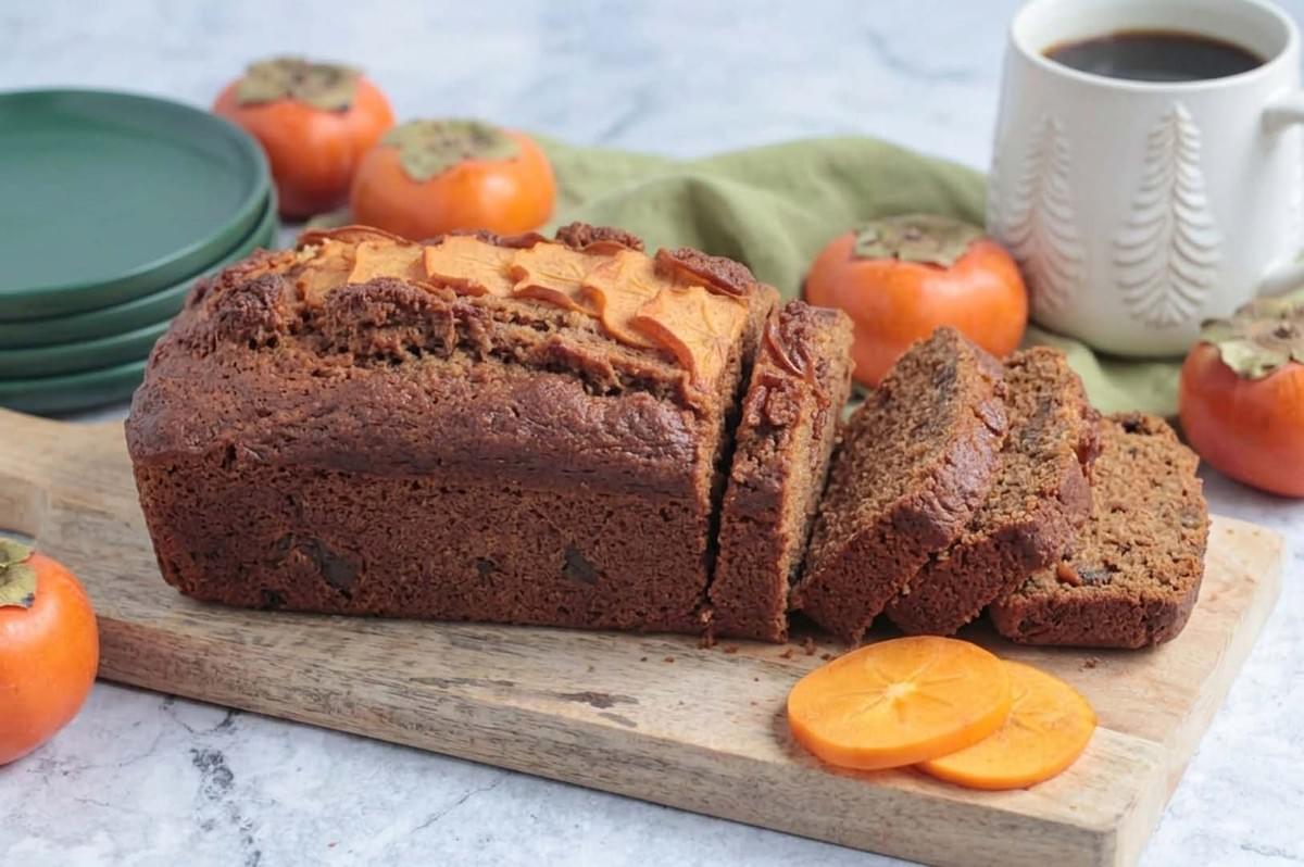 Sliced persimmon bread loaf on cutting board with fresh fruit Sliced persimmon bread loaf on cutting board with fresh fruit