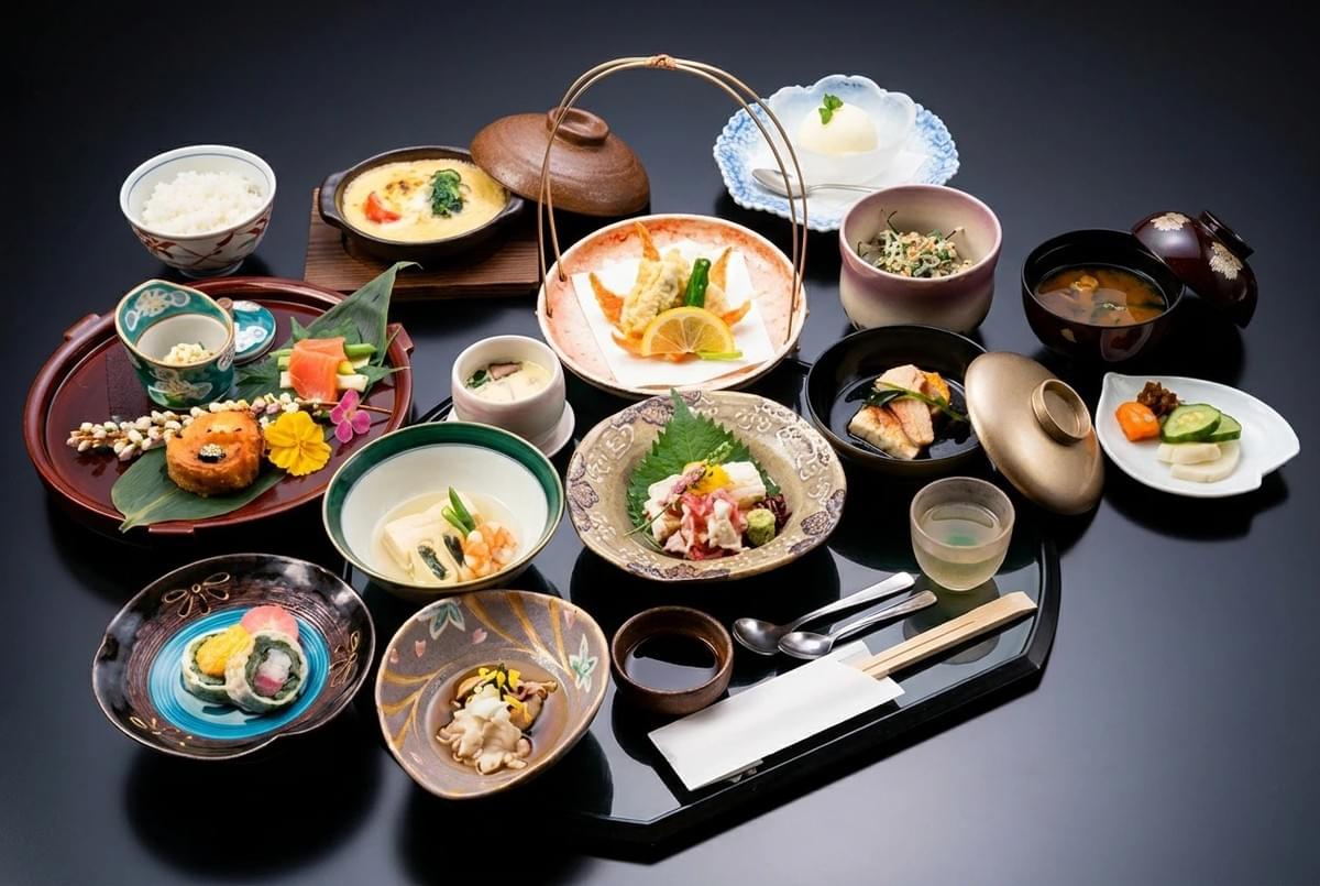 Detailed Japanese set meal featuring tempura, sashimi, side dishes, rice, and soup on a black tray. Detailed Japanese set meal featuring tempura, sashimi, side dishes, rice, and soup on a black tray.