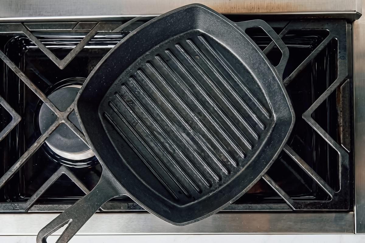 Overhead top-down shot of a cast iron grill pan on a stovetop used for indoor apartment grilling of Indonesian satay chicken skewers Overhead top-down shot of a cast iron grill pan on a stovetop used for indoor apartment grilling of Indonesian satay chicken skewers